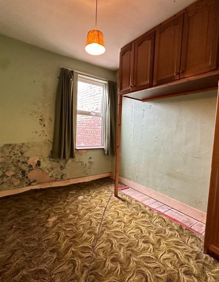 House clearance of a room with old fashioned fitted wardrobe and extreme damp damage to walls after photo